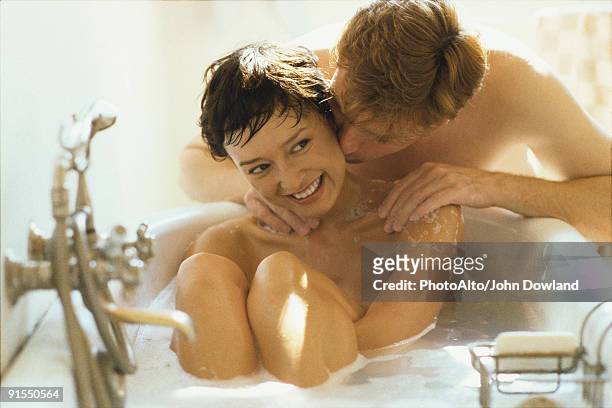 woman relaxing in bathtub, husband kissing her cheek - couple and kiss and bathroom 個照片及圖片檔