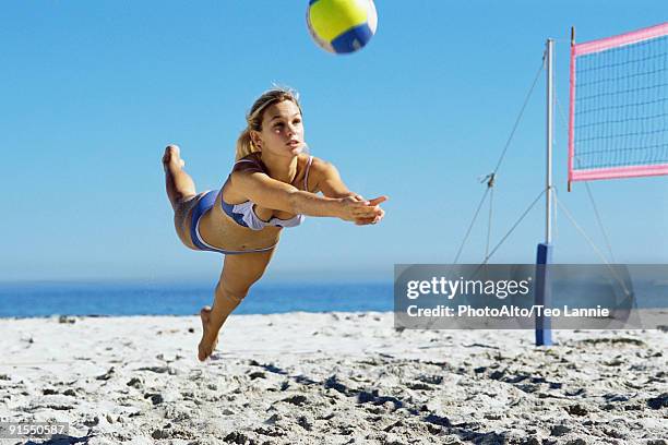 female playing beach volleyball, diving to catch ball - junge frau strand sand springen stock-fotos und bilder