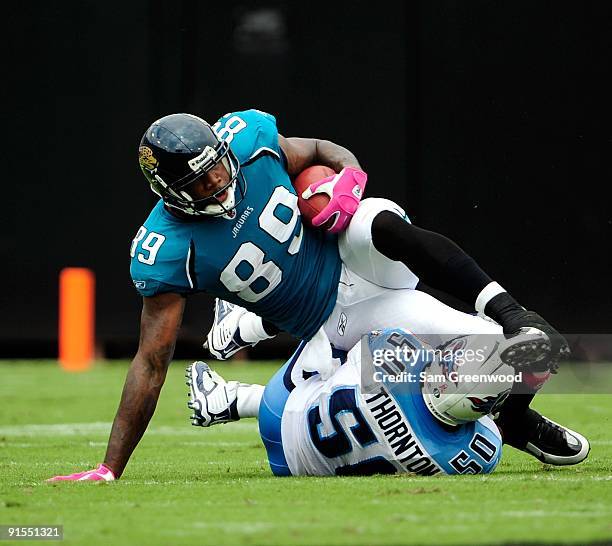 Marcedes Lewis of the Jacksonville Jaguars is tackled by David Thornton of the Tennessee Titans during the game at Jacksonville Municipal Stadium on...