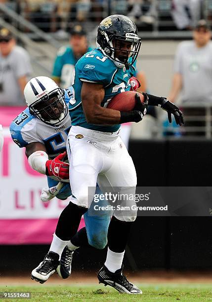 Rashad Jennings of the Jacksonville Jaguars is tackled by Keith Bullock of the Tennessee Titans during the game at Jacksonville Municipal Stadium on...