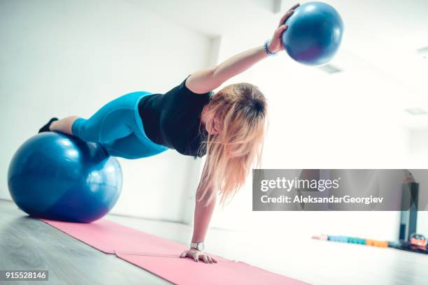 atleta mujer haciendo equilibrio pilates ejercicios en pelota fitness en gimnasio - yoga ball fotografías e imágenes de stock