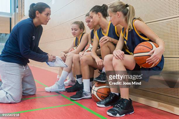 female basketball coach teaching young players, using clipboard - basketball sport stock-fotos und bilder