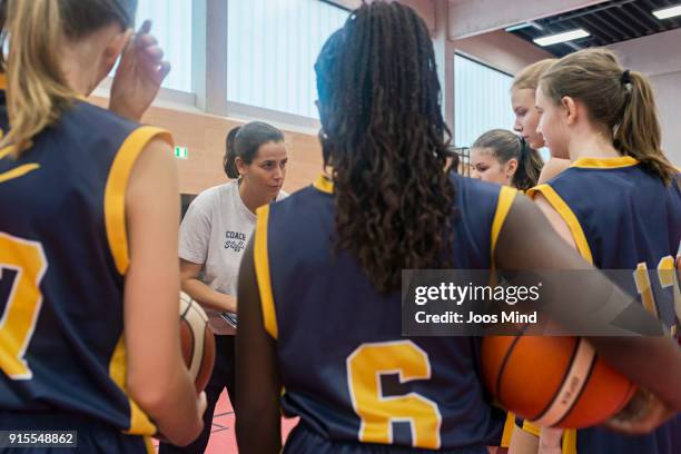 female basketball coach teaching young players, huddling in circle - basketball team stock pictures, royalty-free photos & images