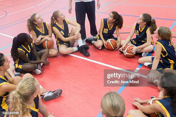 female basketball coach teaching a group of young players - basketbal teamsport stockfoto's en -beelden
