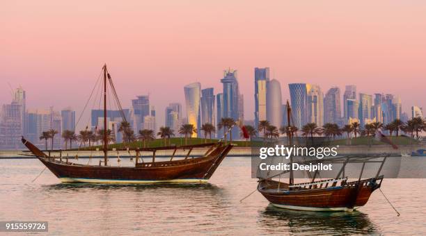 the downtown doha city skyline and traditional boom boat at sunset, qatar - doha sunset stock pictures, royalty-free photos & images