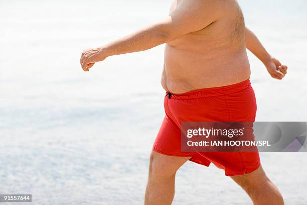 man walking on beach - fat guy on beach fotografías e imágenes de stock