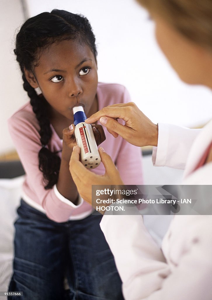 Girl(8-9) breathing into peak flow meter (spirometer)