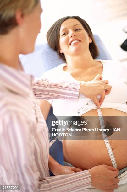 midwife (left) measuring size of pregnant woman's abdomen - midwife stock pictures, royalty-free photos & images