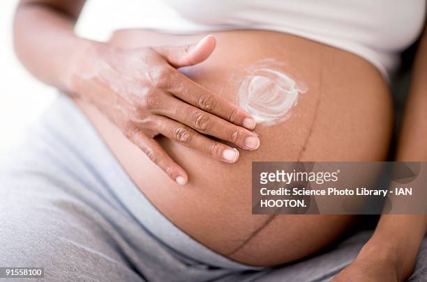 pregnant woman applying cream to stretch marks - stretch mark stock pictures, royalty-free photos & images