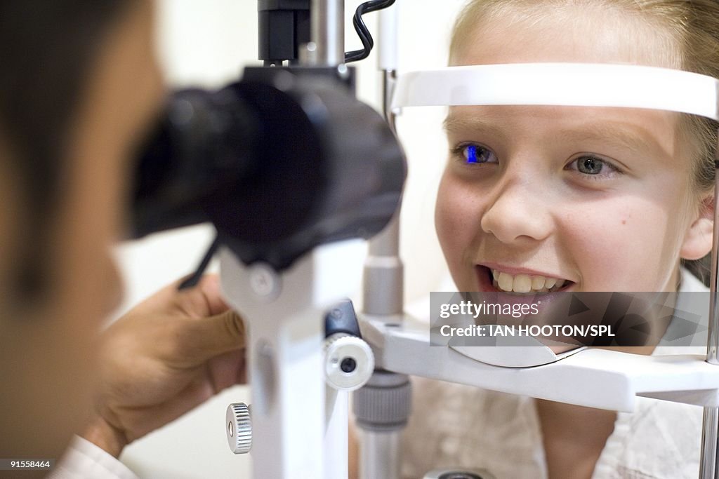 Optician using lit lamp to examine girl's eyes (10-11)