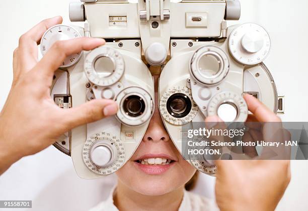 optometrist (optician) examining eye of woman - réfracteur photos et images de collection