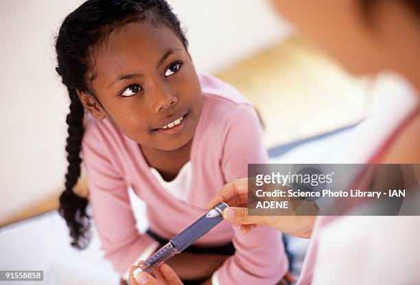 girl (8-9) looking at doctor holding insulin syringe - child diabetes stock pictures, royalty-free photos & images