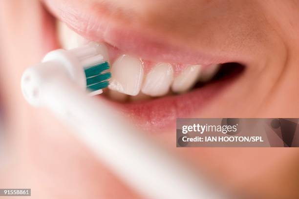 woman cleaning teeth with electric toothbrush, close-up - elektrische zahnbürste stock-fotos und bilder