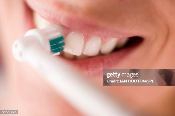 woman cleaning teeth with electric toothbrush, close-up - spazzolino elettrico foto e immagini stock
