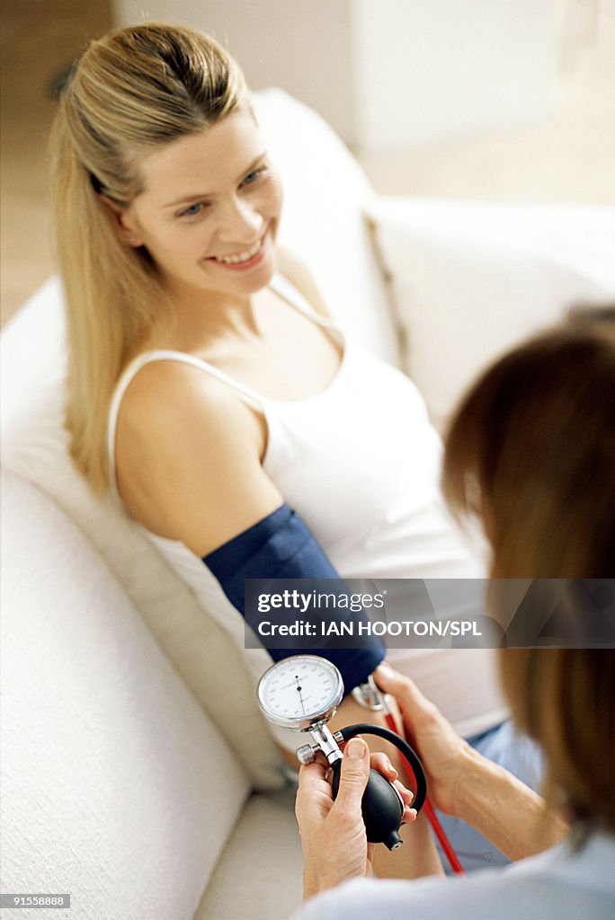 Doctor checking woman's blood pressure