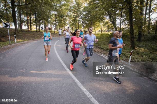 grupo grande de personas que corren un maratón en carretera asfaltada en la naturaleza. - 10000 metros fotografías e imágenes de stock