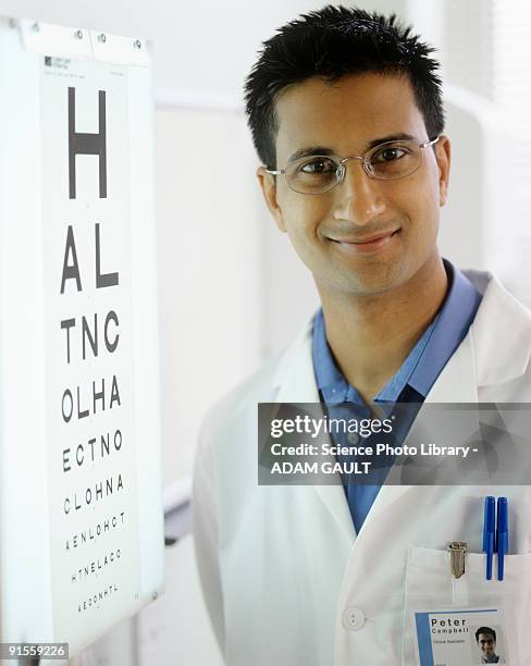 optometrist next to eye chart, smiling - ophthalmologist chart stock pictures, royalty-free photos & images