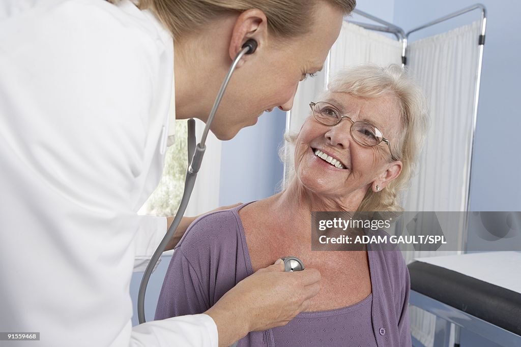 Medical consultation, general practitioner using stethoscope to examine elderly patient