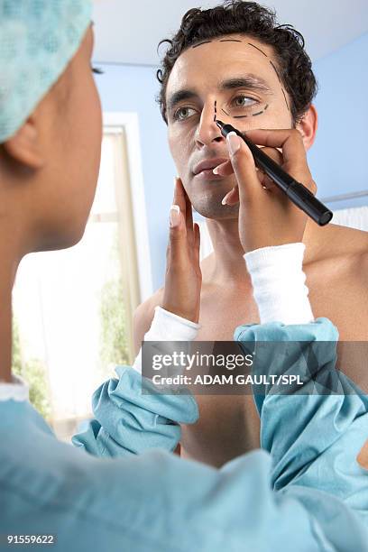 surgeon drawing marks on patient's face - cirugía plástica hombres fotografías e imágenes de stock