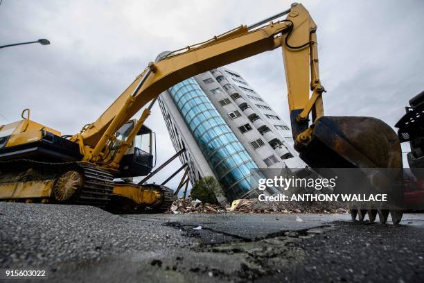 Heavy construction vehicle is seen parked in front of the Yun Tsui building, which is leaning at a precarious angle, in the Taiwanese city of Hualien...