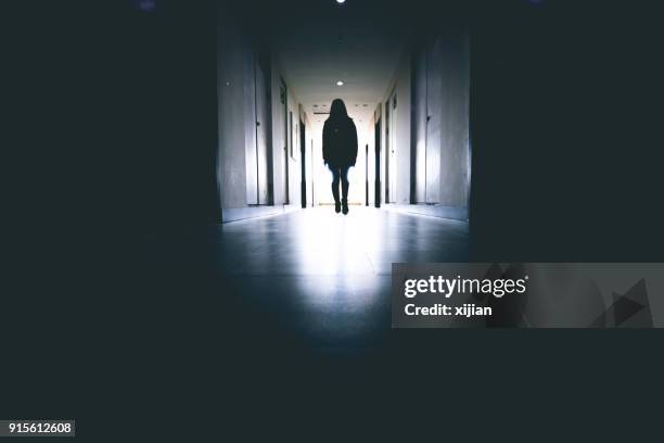 woman standing in a corridor - woman walking out door silhouette stock pictures, royalty-free photos & images