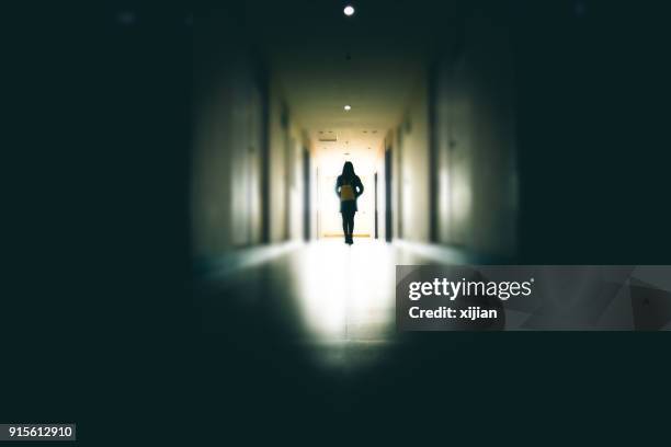 young woman in dark building walkway - dark corridor stock pictures, royalty-free photos & images