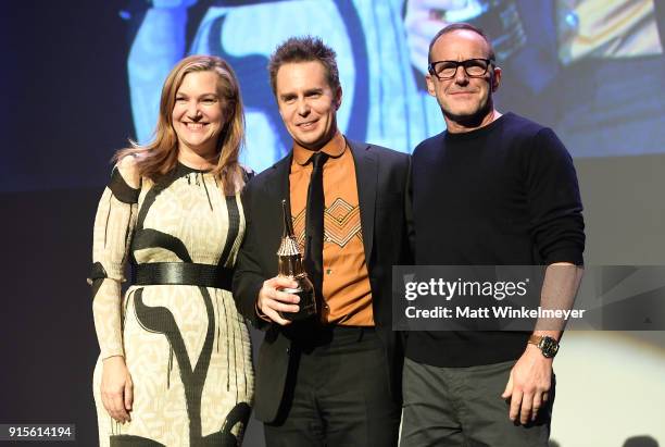 Moderator Krista Smith, actors Sam Rockwell and Clark Gregg pose onstage with The American Riviera Award at The American Riviera Award Honoring Sam...