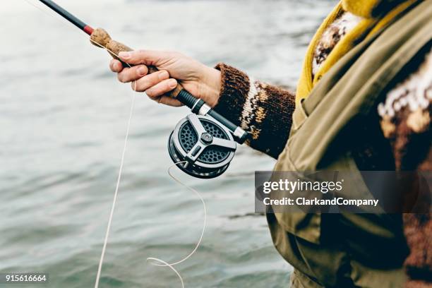 fisherman tying a fly onto her line - rod stock pictures, royalty-free photos & images