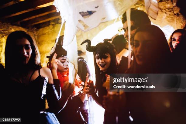 junge freunde in halloween-kostümen tanzen und trinken auf party - halloween party stock-fotos und bilder
