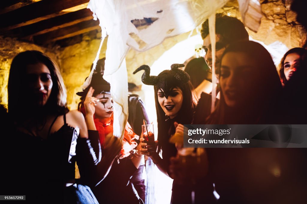 Jonge vrienden in Halloween kostuums dansen en drinken op feestje