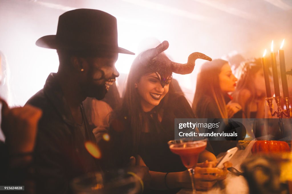 Multi-ethnischen Jugendliche in Kostümen SMS bei Halloween-party