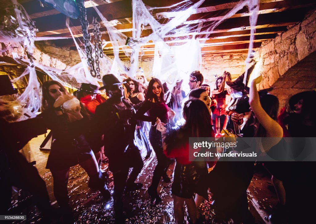 Multi-ethnic people in Halloween costumes having fun at dungeon nightclub