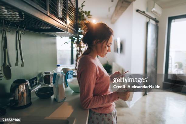young woman drinking first morning coffee - mobile devices at home stock pictures, royalty-free photos & images