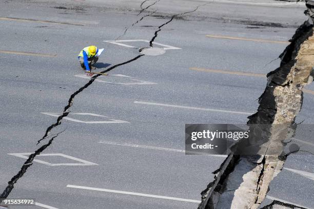 Chinese employee investigates the scene of accident after a road collapse in Foshan in China's southern Guangdong province on February 8, 2018. -...