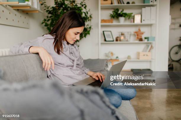 junge frau benutzt einen computer zu hause - couch laptop stock-fotos und bilder