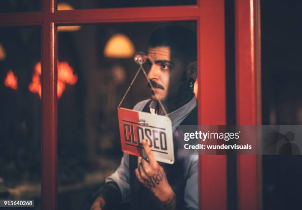 jonge mannelijke-ondernemer die zijn bedrijf gesloten shop teken ter venster - barber shop stockfoto's en -beelden
