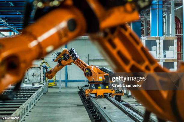 bracci robotici che lavorano sulla catena di montaggio - robotica foto e immagini stock