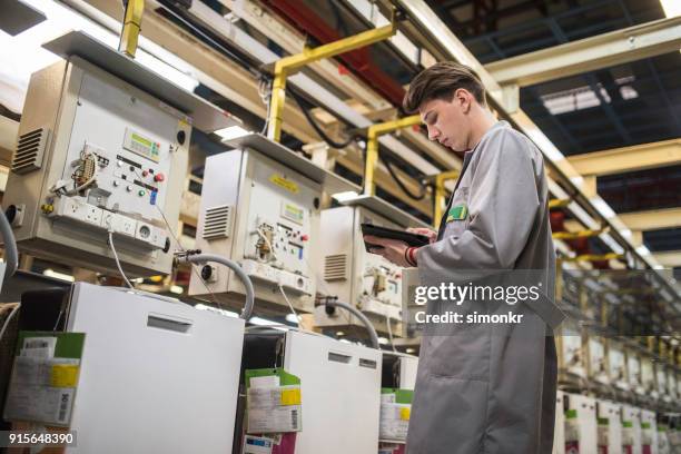 factory worker entering data into digital tablet - appliance manufacturing stock pictures, royalty-free photos & images