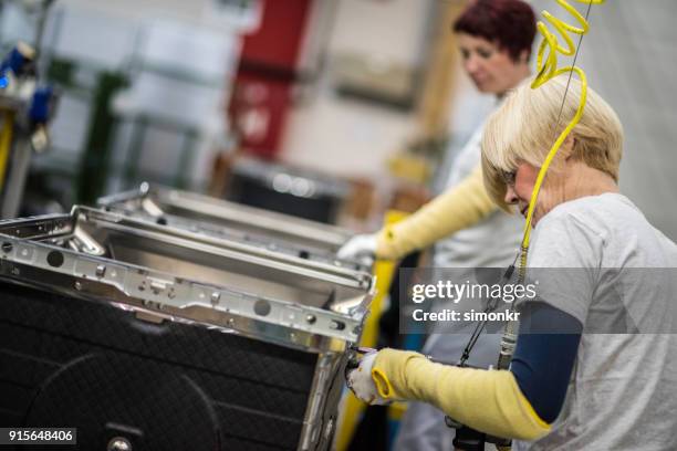 fabrikarbeiter, anziehen der schrauben auf produkt - hineinstecken stock-fotos und bilder