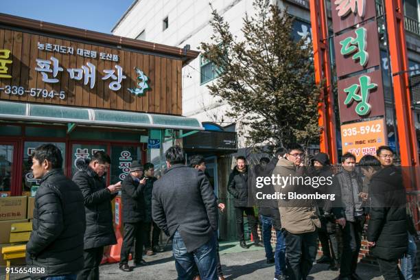 People smoke cigarettes outside a restaurant in the Hoenggye-ri village area of Pyeongchang, Gangwon Province, South Korea, on Thursday, Feb. 8,...