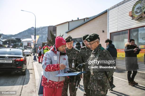 Volunteer, left, speaks with South Korean soldiers ahead of the 2018 PyeongChang Winter Olympic Games in the Hoenggye-ri village area of Pyeongchang,...