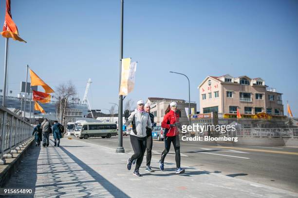 Pedestrians jog across a bridge in the Hoenggye-ri village area of Pyeongchang, Gangwon Province, South Korea, on Thursday, Feb. 8, 2018. North...