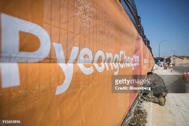 Worker hangs a banner on a fence ahead of the 2018 PyeongChang Winter Olympic Games in the Hoenggye-ri village area of Pyeongchang, Gangwon Province,...