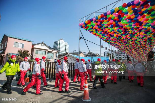 Olympic volunteers walk under balloon decorations ahead of the 2018 PyeongChang Winter Olympic Games in the Hoenggye-ri village area of Pyeongchang,...