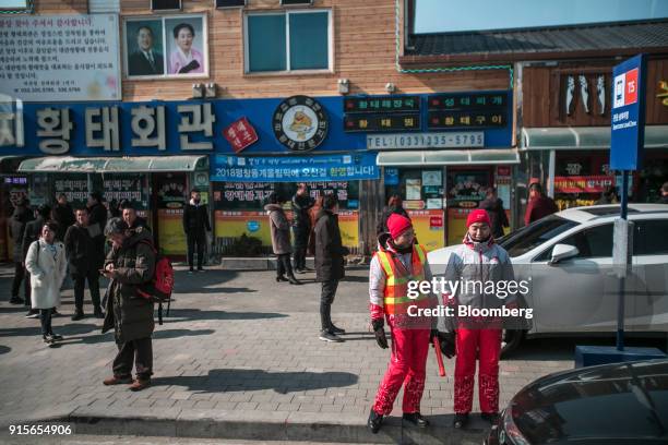 Olympic volunteers stand along a road in the Hoenggye-ri village area of Pyeongchang, Gangwon Province, South Korea, on Thursday, Feb. 8, 2018. North...