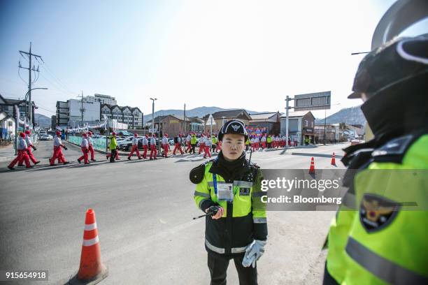 Police officers stand guard as Olympic volunteers walk along a road ahead of the 2018 PyeongChang Winter Olympic Games in the Hoenggye-ri village...