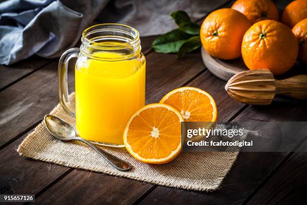 barattolo di vetro succo d'arancia girato su un tavolo rustico in legno - agrumi foto e immagini stock