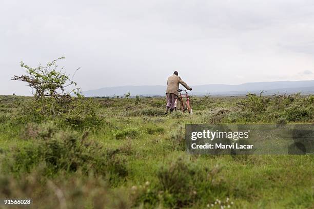 Pastor William Nkurumwa walks his bicycle accross the muddy expanse December 23, 2006 in Olamanera, Kenya. Pastor William assisted a relative, Takaya...