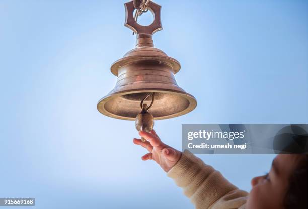 an indian woman and child ring brass temple bell that hang. - indian temples stock pictures, royalty-free photos & images