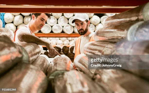 zwei männer diskutieren teppiche im lager sammellager - blick durch kameraobjektiv stock-fotos und bilder